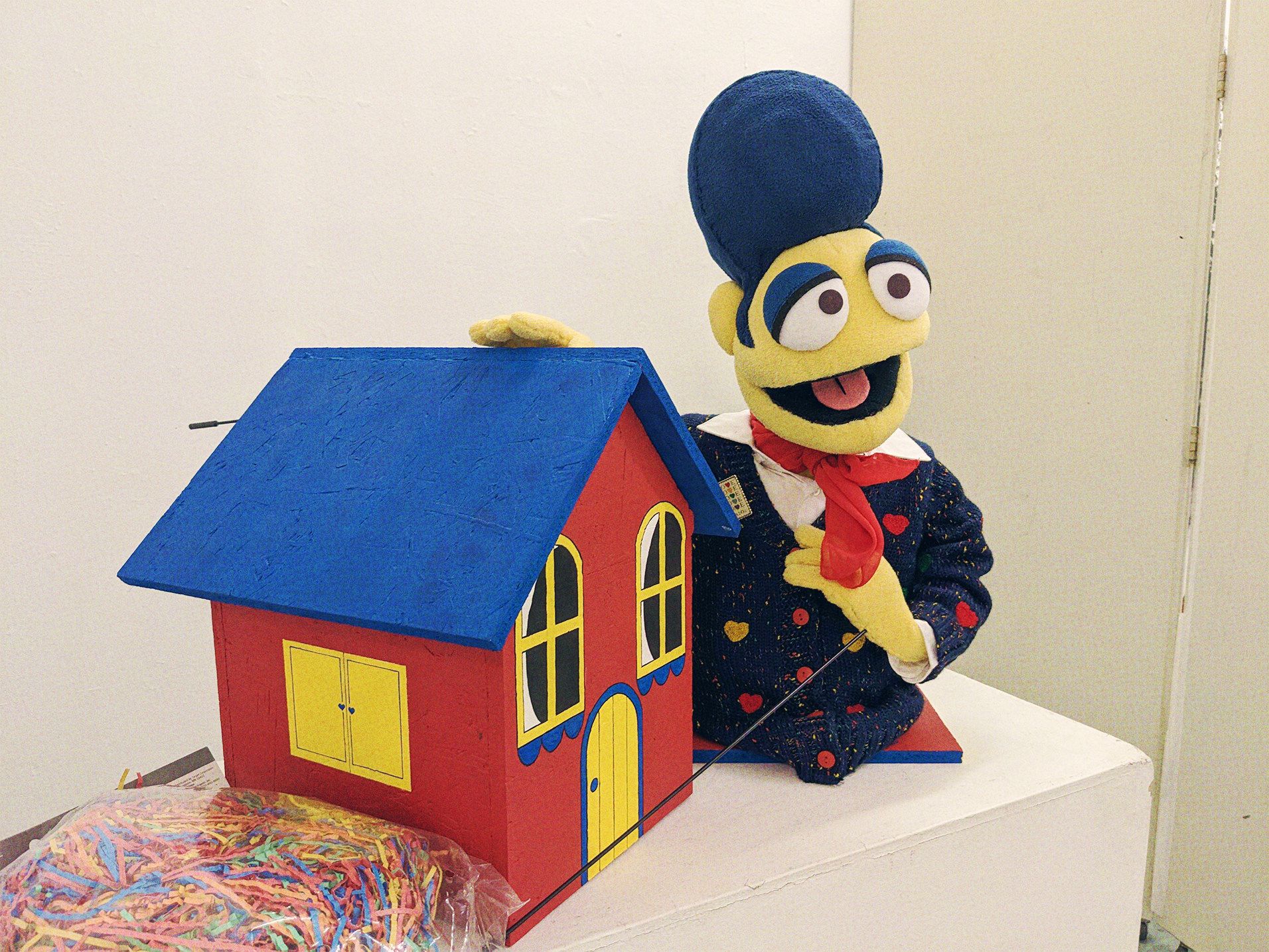 A photograph of a Wally Darling replica puppet, and a wooden home.