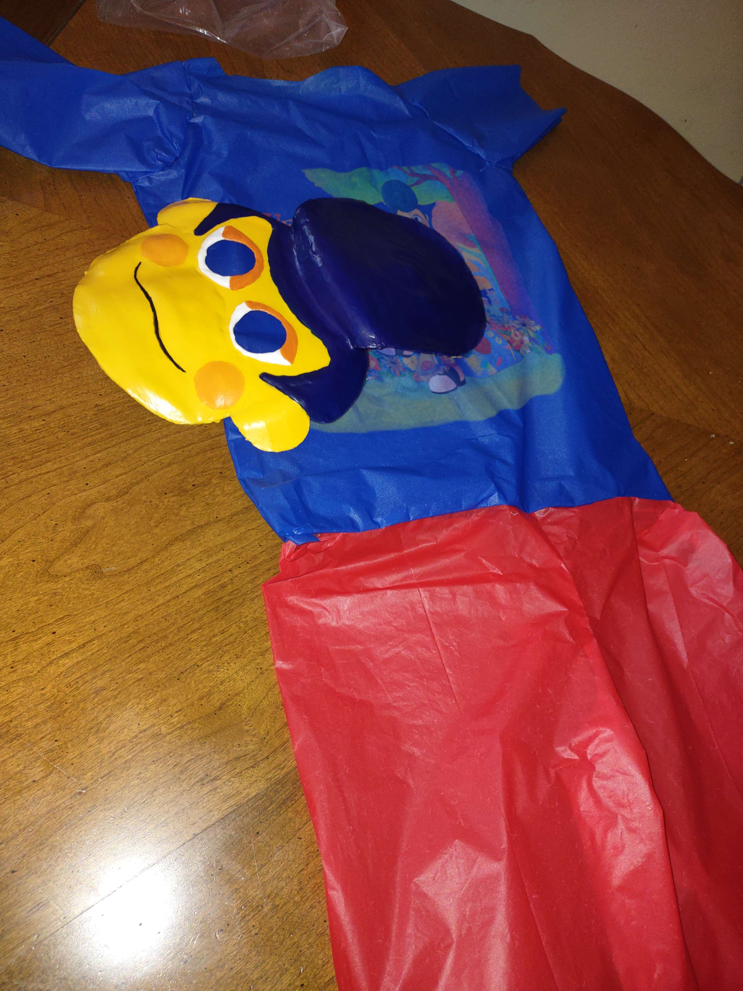 A photo showing the Wally Darling halloween costume laid out on a wooden table. It includes a connected blue shirt and red pants, as well as a Wally mask.