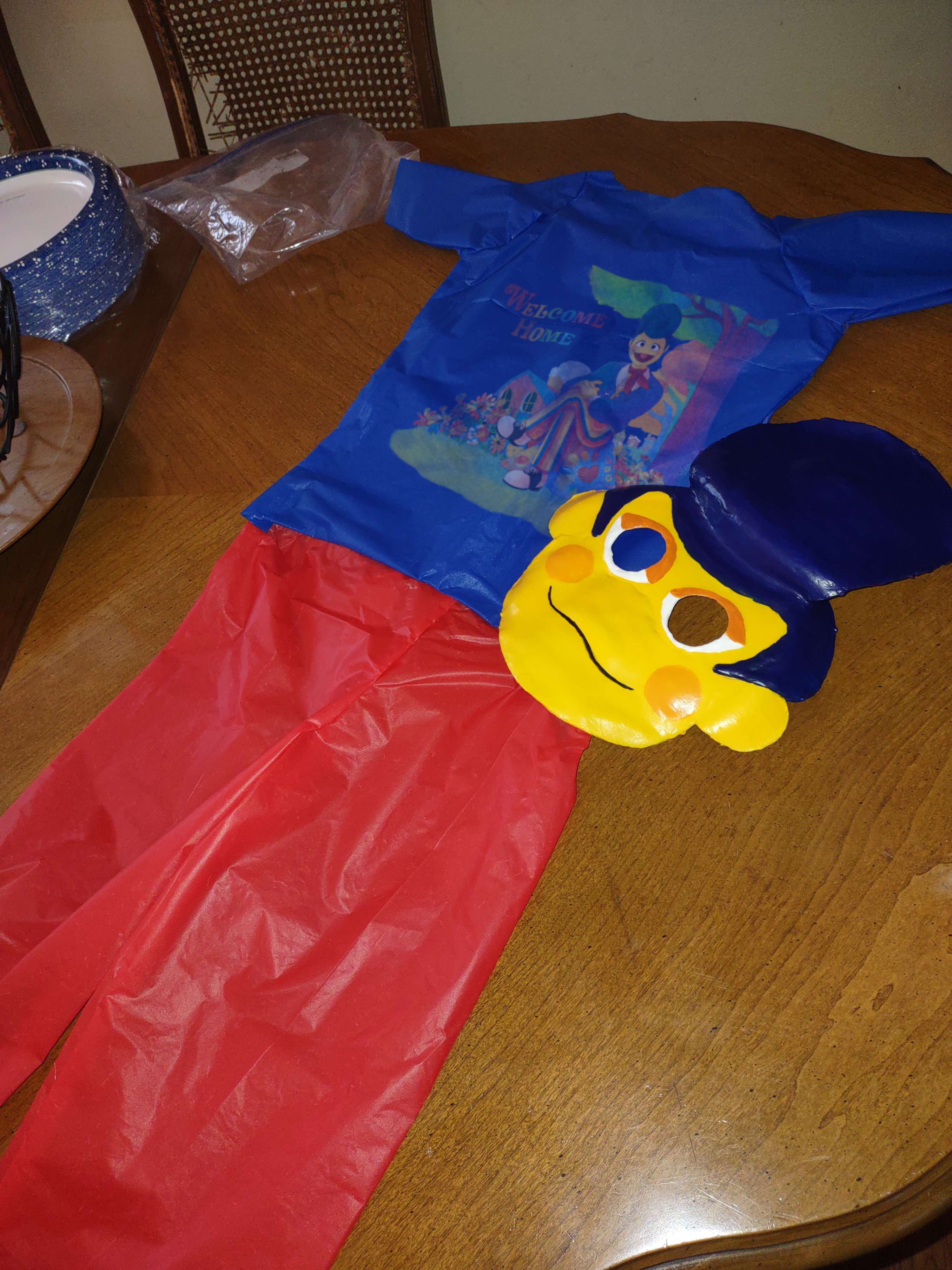 Another photo showing off the costume, this time the mask is set slightly to the side to better show off that the shirt has an illustration of Wally sitting under a tree with Home in the background alongside the logo.