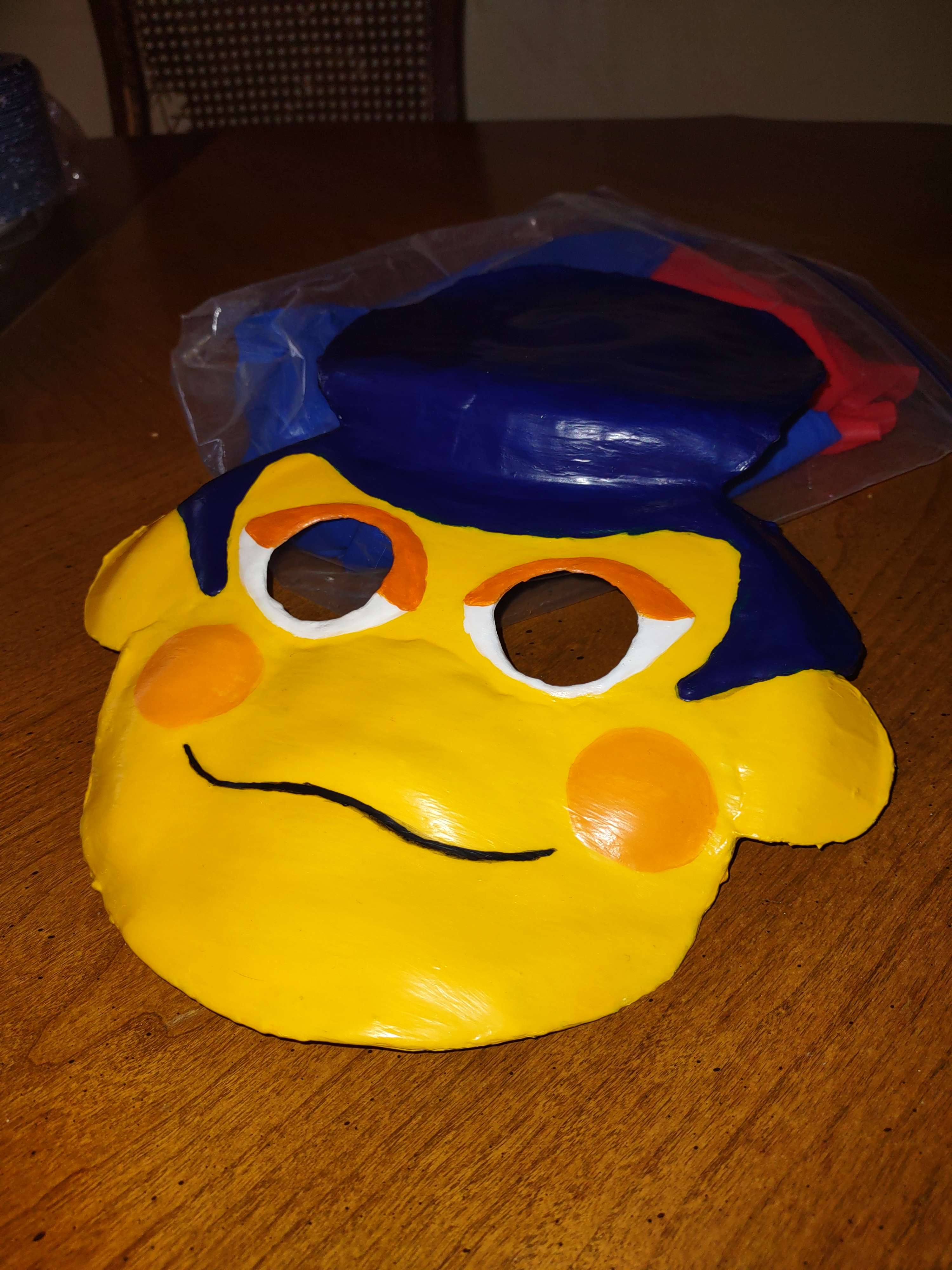 A closeup shot of the Wally mask, it has a painted on smile and holes so the mask wearer can see, as well as orange spots on his cheeks and faithfully recreates his blue hair do.